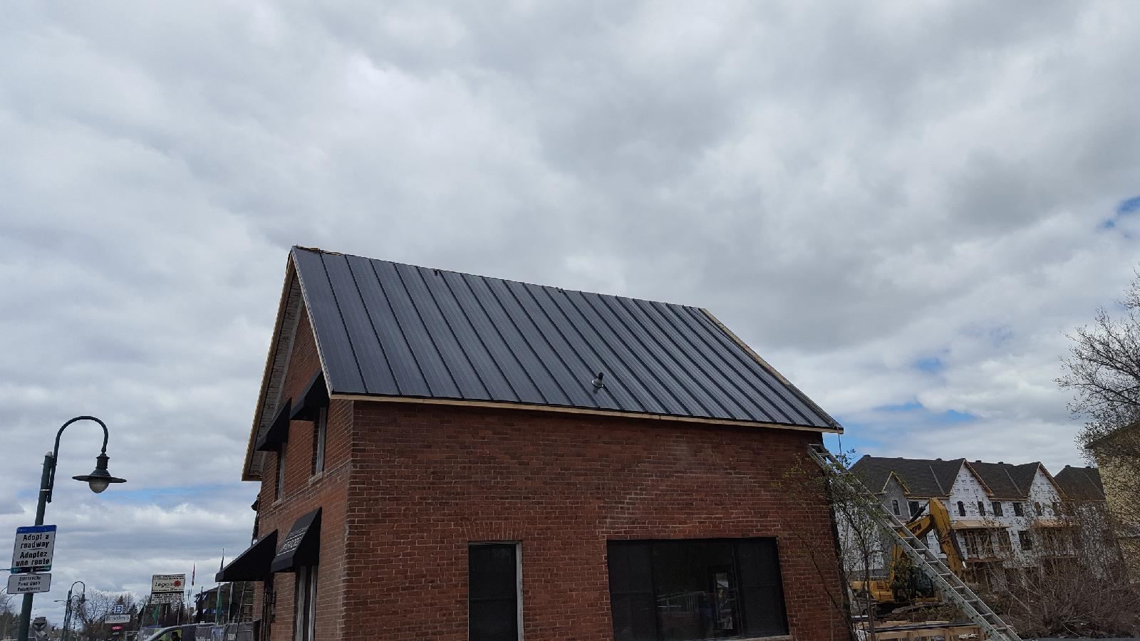 A new standing-seam metal roof on a red brick building
