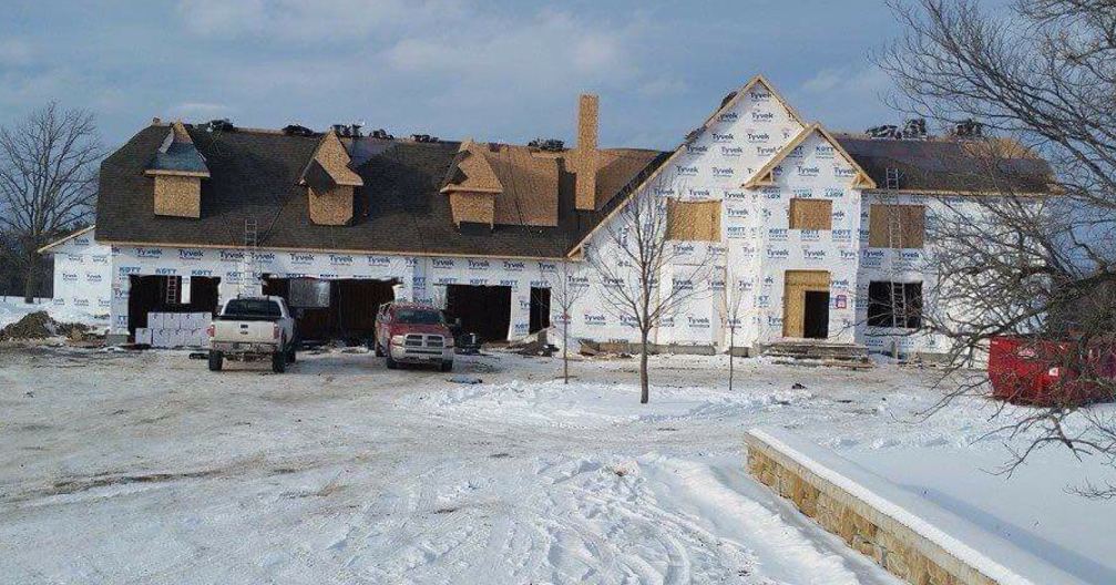A large new house with dormers, roofed in winter snow